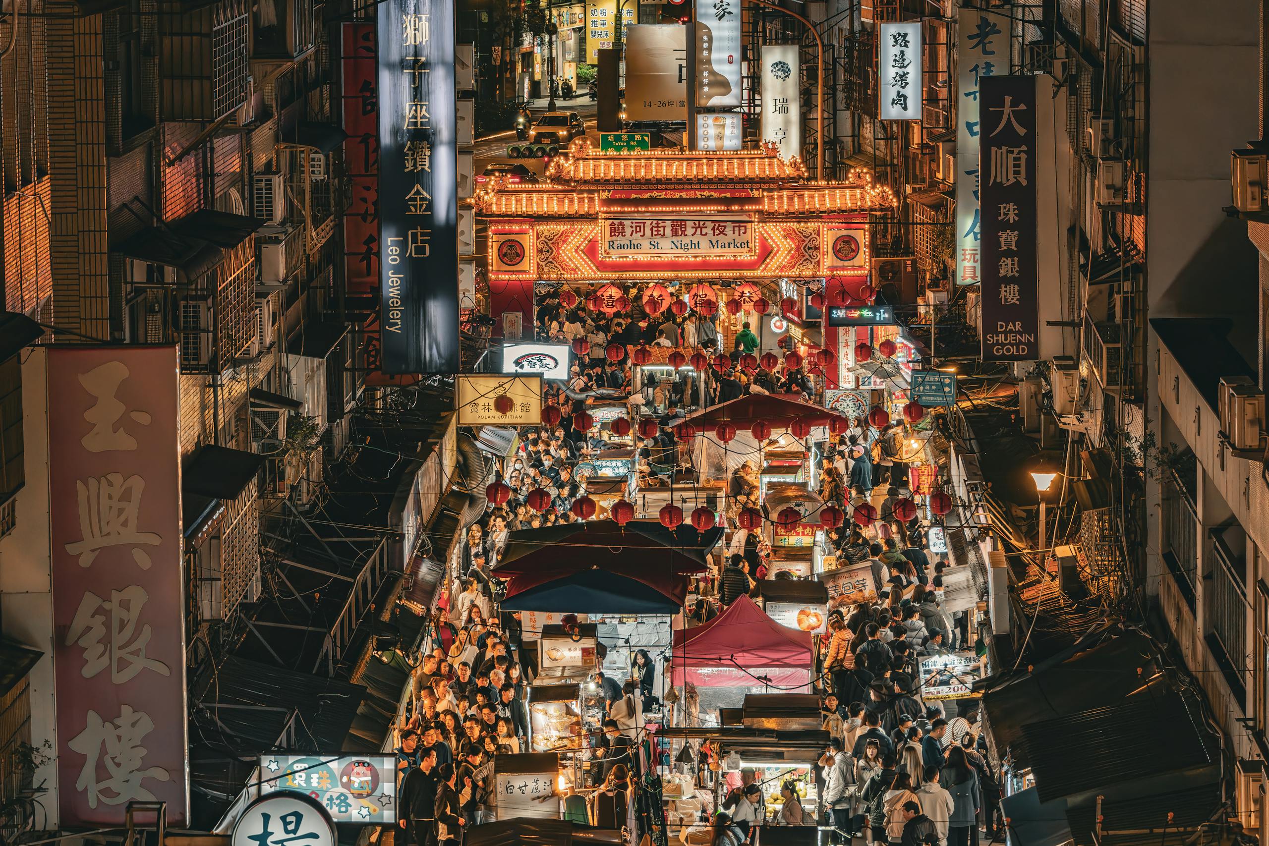 Bustling night market scene at Raohe Street, Taipei, showcasing vibrant street life and illuminated stalls.